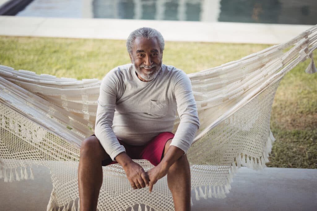 Portrait of smiling senior man sitting on hammock