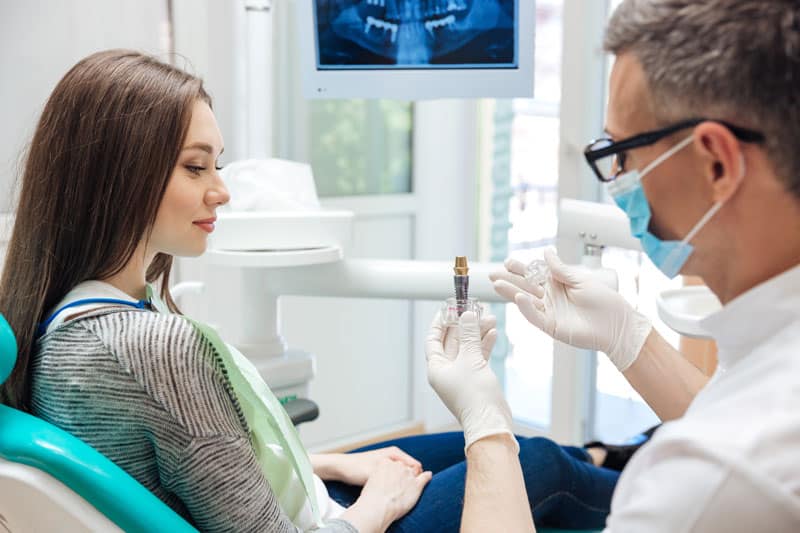 girl in dental chair listening to doctor explain a tooth replacement solution